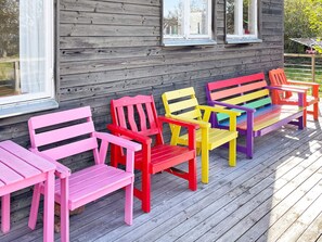 Um deck de madeira com cadeiras Adirondack coloridas.