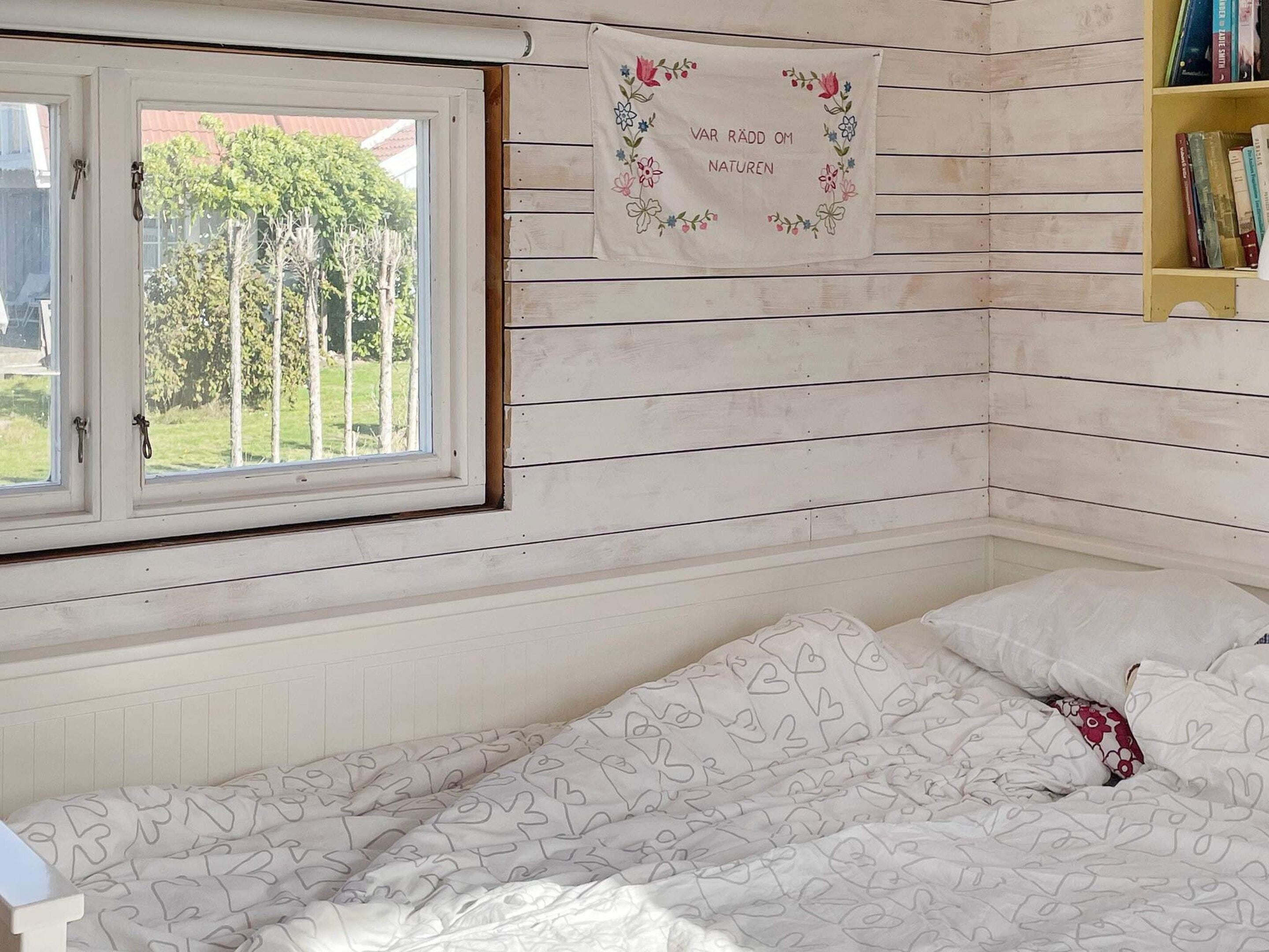 Un dormitorio con cama, ventana y estantería.