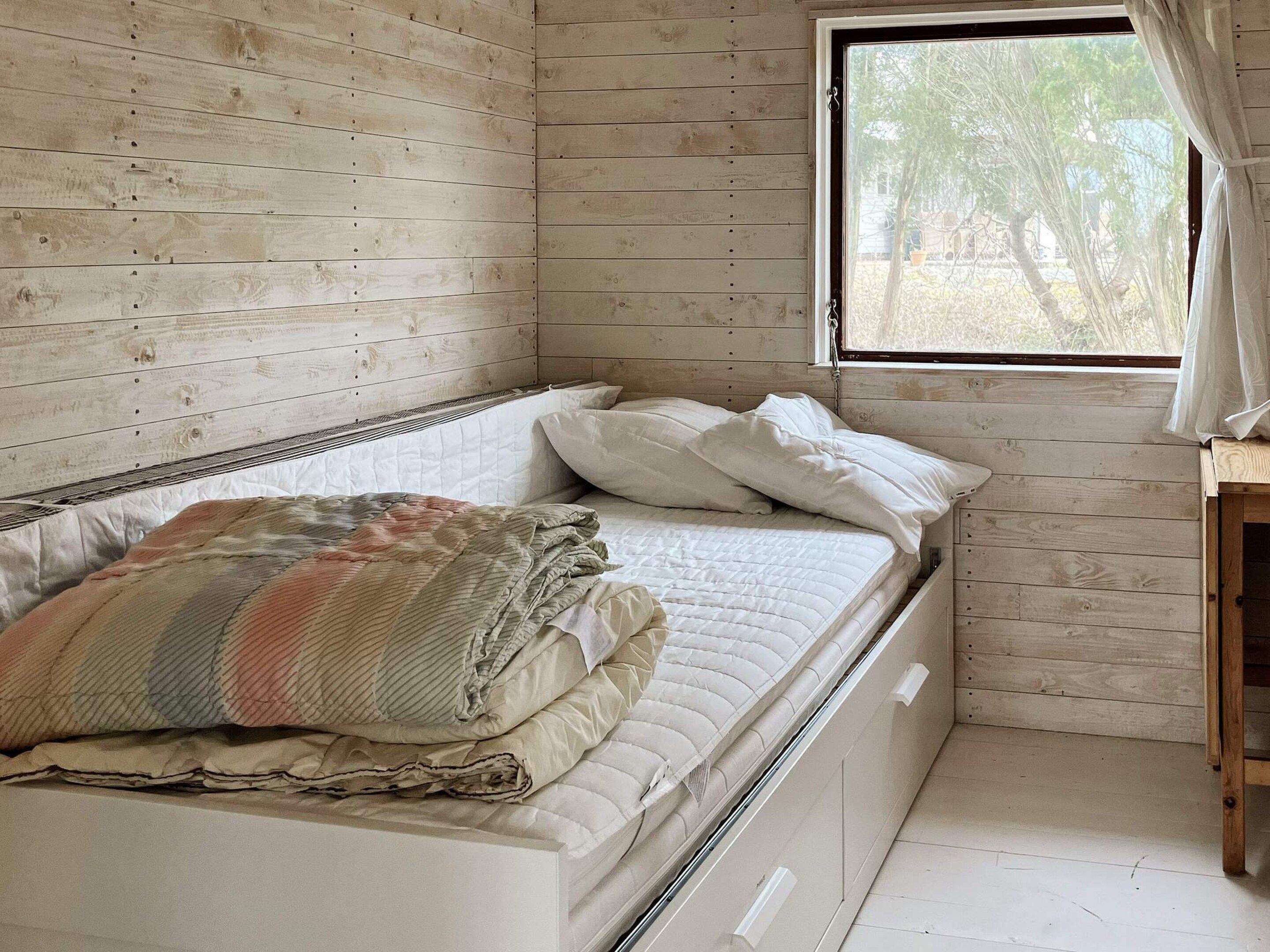 A bed with a quilt, pillows, and a window with curtains.
