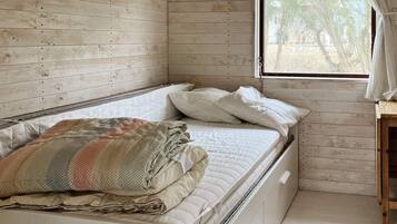 A bed with a quilt, pillows, and a window with curtains.