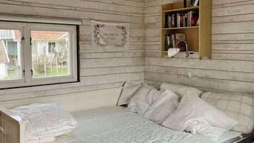 Un dormitorio con una cama, una ventana, una estantería y un adorno de pared.