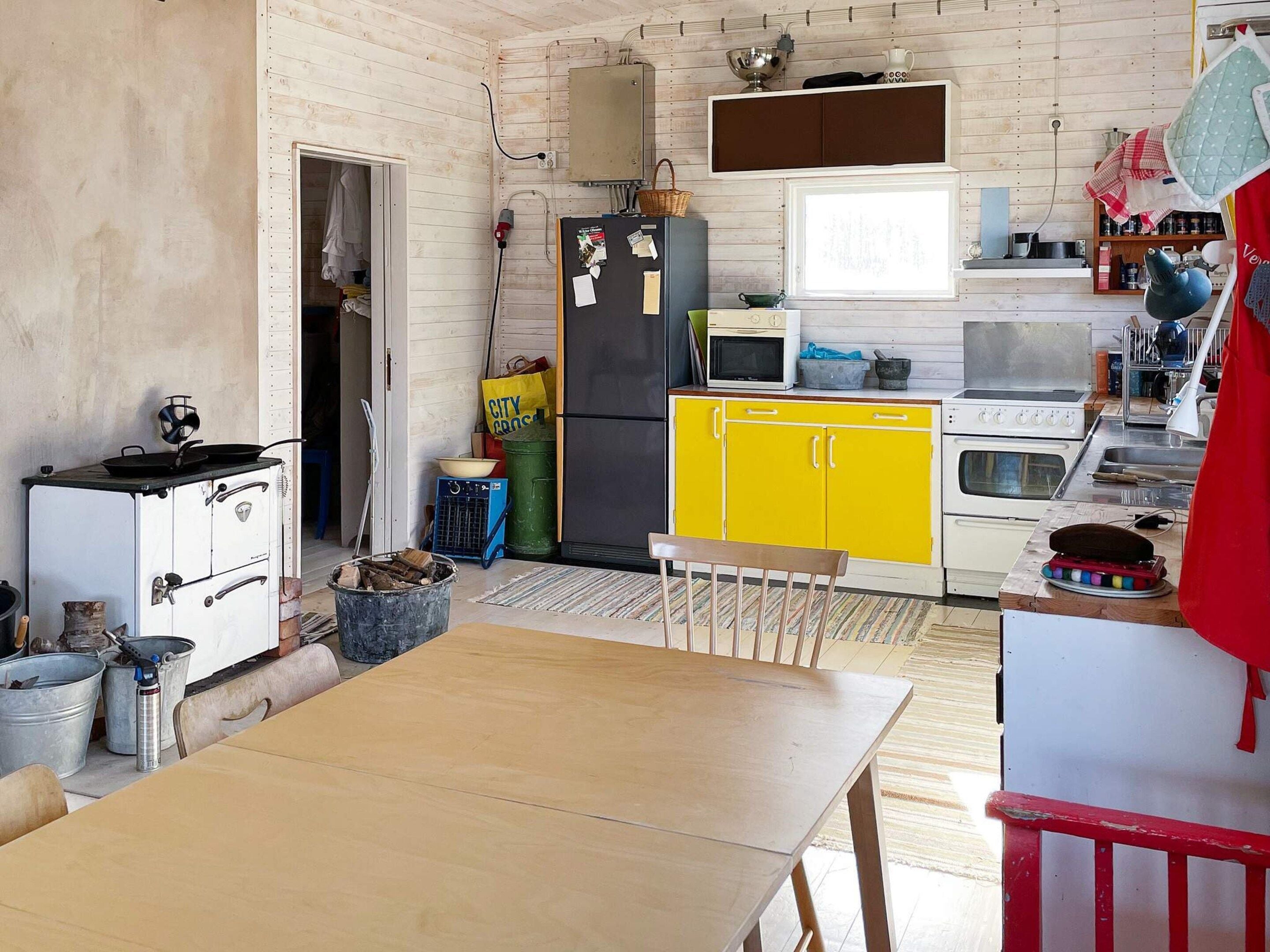 Una cocina compacta con una mesa de madera, un refrigerador, un microondas y una estufa.