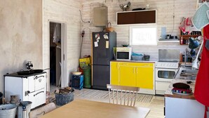 A compact kitchen with a wooden table, a refrigerator, a microwave, and a stove. - 4 Star Holiday Home in Sturko (Sturkö)