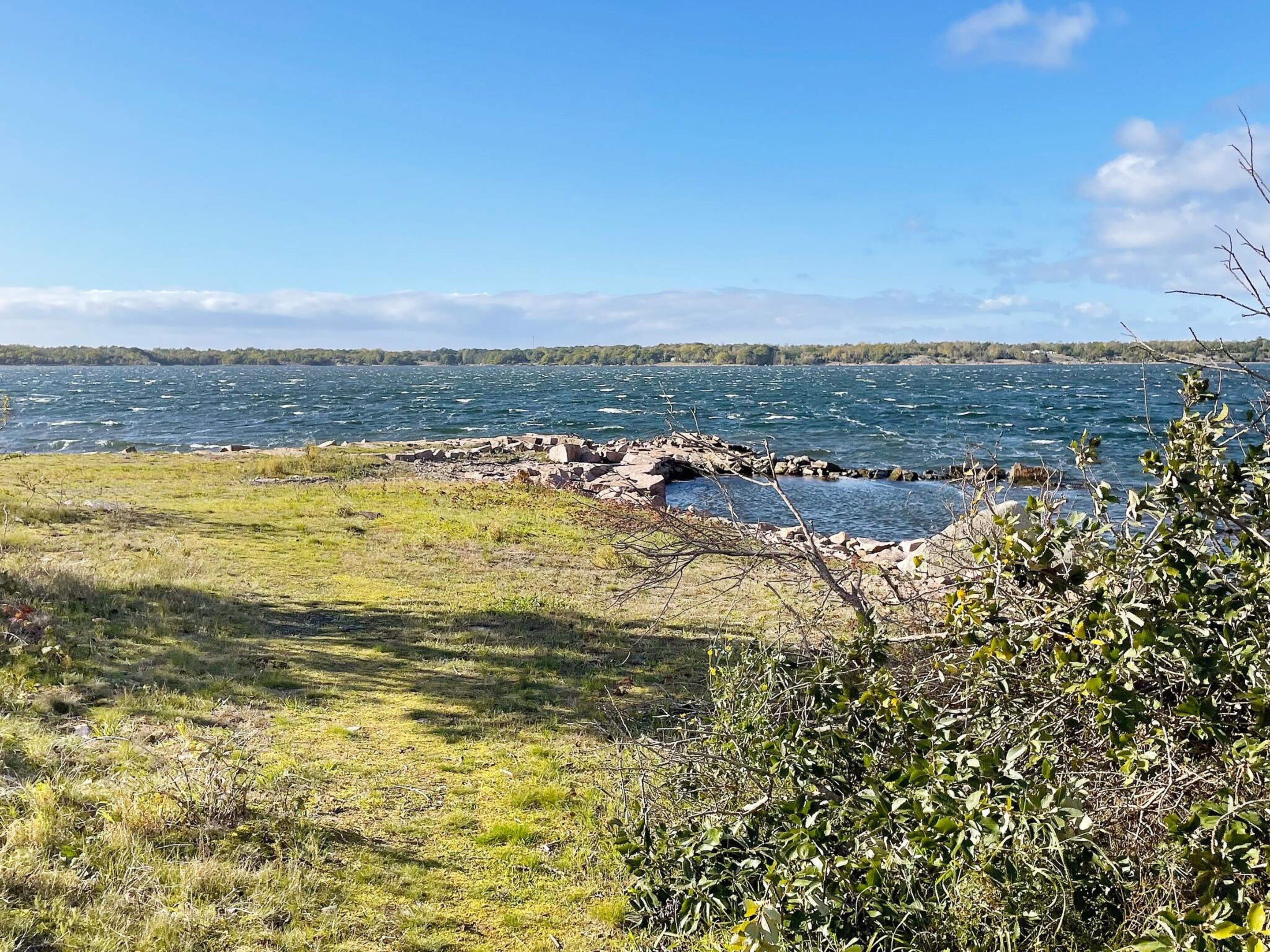 A natural landscape with a body of water, rocky shoreline, and vegetation.