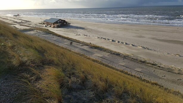 A beach with a building and a boardwalk. - Sunshine Comfortable Holiday Residence (Sint Maarten)