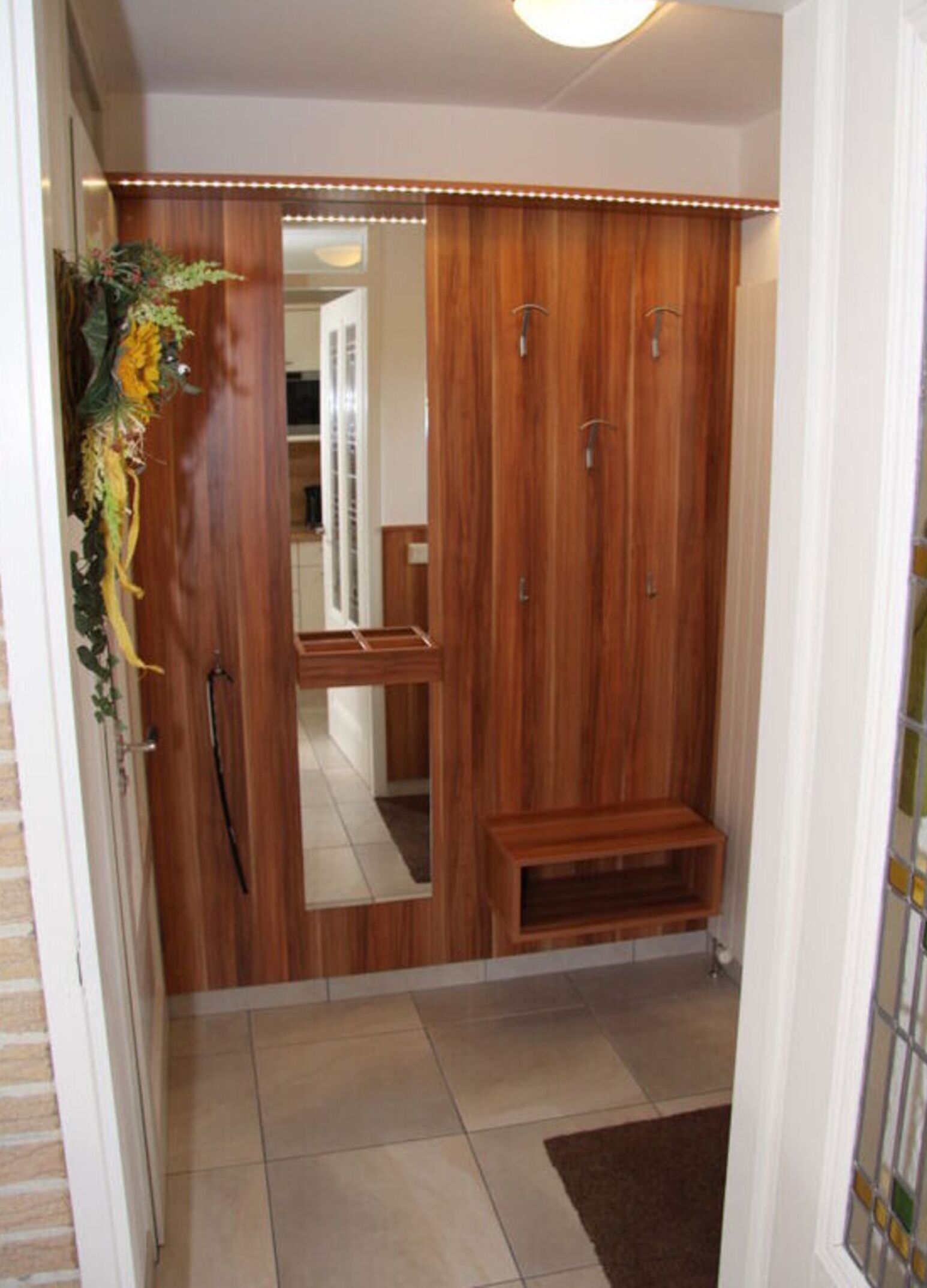 A hallway with a wooden wardrobe, a mirror, and a bench.