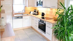 A modern kitchen with white cabinets, a wooden countertop, a coffee maker, and a sink. - Sunshine Comfortable Holiday Residence (Sint Maarten)