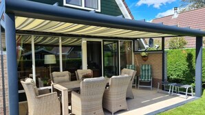 A covered patio with wicker furniture, a table, and chairs. - Sunshine Comfortable Holiday Residence (Sint Maarten)