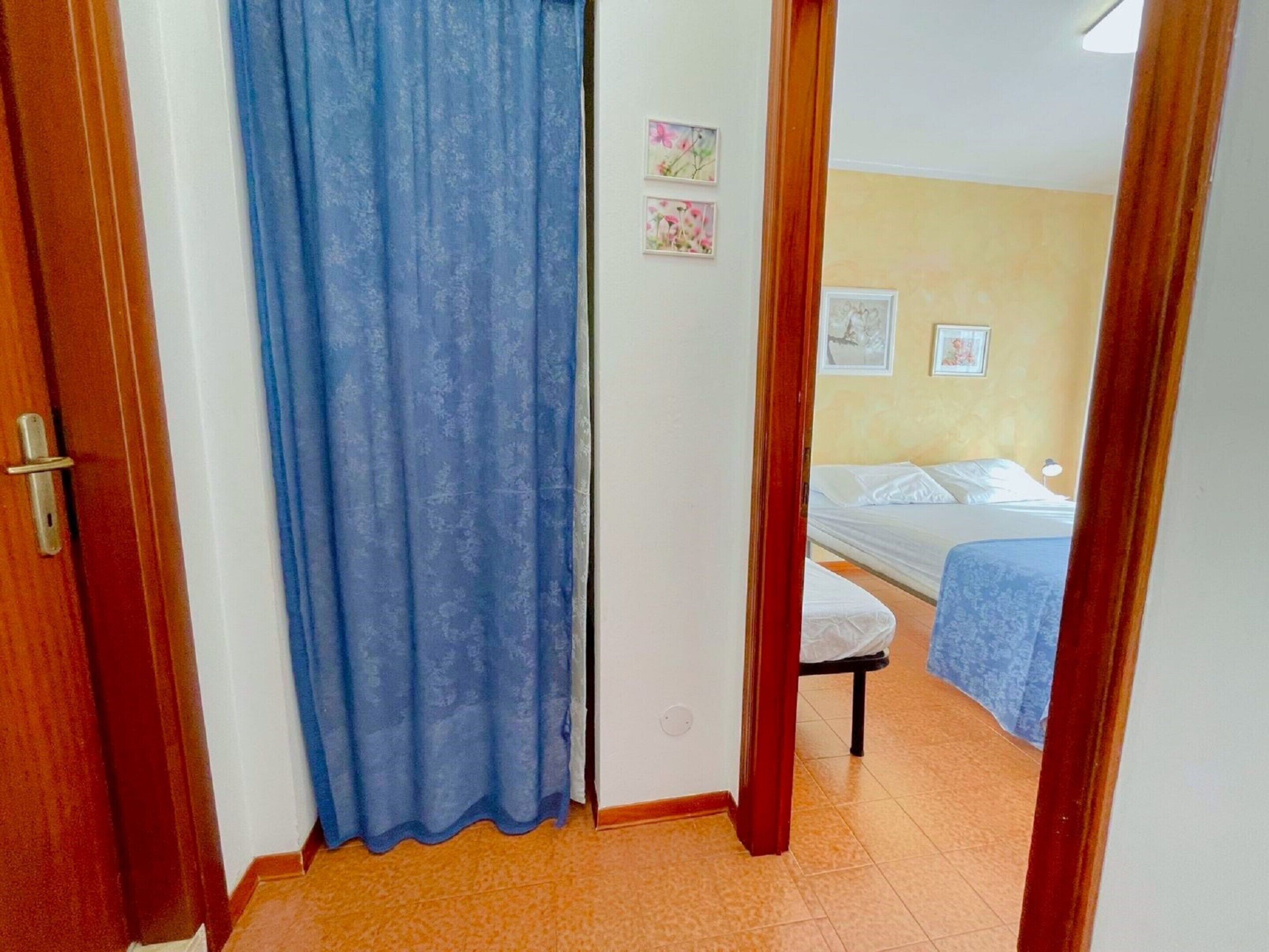 Een kamer met een bed, een klein tafeltje en een blauw gordijn.