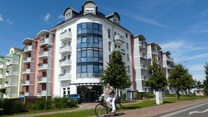A multi-story residential building with balconies, a central glass facade, and a cyclist on the sidewalk. - Amazing Apartment in Templin (Templin)