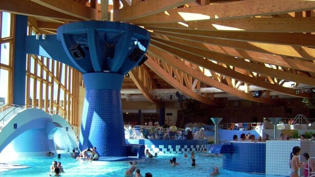 An indoor swimming pool with a large blue water feature and wooden beams. - Amazing Apartment in Templin (Templin)