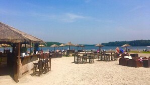 A beachside area with thatched-roof structures, wooden tables, and umbrellas. - Amazing Apartment in Templin (Templin)