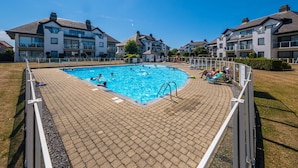A swimming pool surrounded by a brick deck, with a clear blue sky above. - Cozy Apartment With Sunny Terrace (Middelkerke)