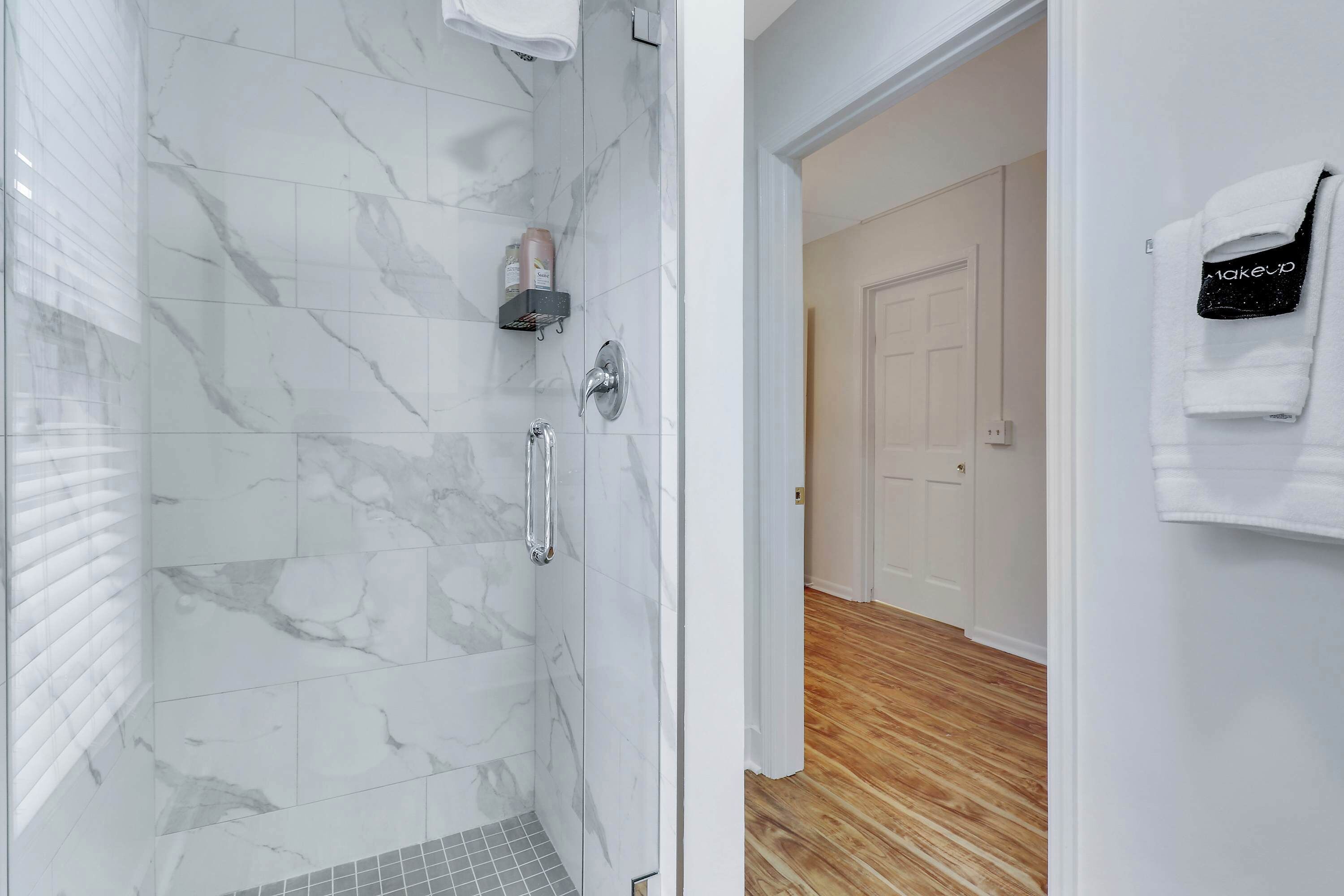 Une salle de bain moderne avec des carreaux de marbre, une douche et un plancher en bois.