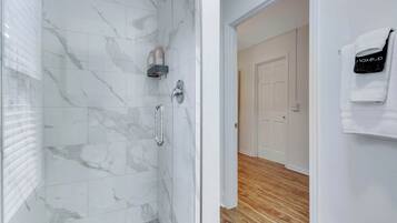 Une salle de bain moderne avec des carreaux de marbre, une douche et un plancher en bois.