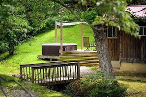 A wooden deck with a bench, a TV on a stand, and a chair.