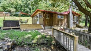 Una baita di legno con tetto rosso, un patio e un piccolo portico.