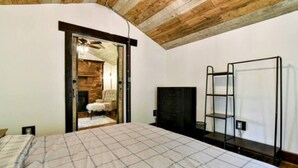 Una camera da letto con un letto, un armadio, una TV e una porta che dà su un soggiorno.