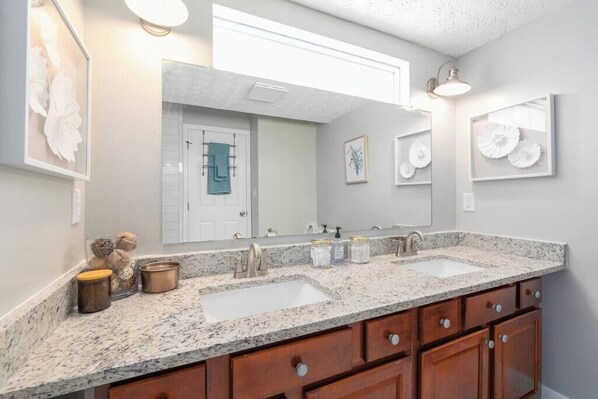 A bathroom with two sinks, wooden cabinets, and wall-mounted lights.