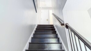 Eine Treppe mit dunklen Holzdielen führt zu einer weißen Tür oben.