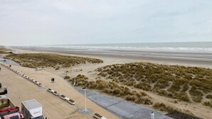 A beachside view with a paved walkway, benches, and a parking area. - Couple Stay Near Beaches (Nieuwpoort)