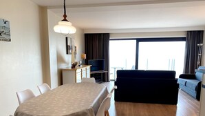 A modern living room with a dining area, a sofa, and a TV. - Couple Stay Near Beaches (Nieuwpoort)