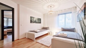 A modern bedroom with a large bed, a smaller bed, a sofa, a painting, and a view of the city. - "Sweet Home" (Central & Quiet) **** (München)
