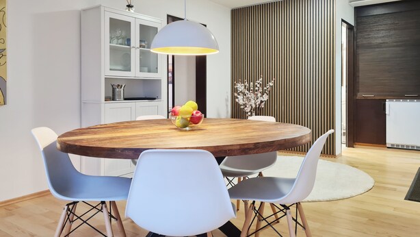 A modern dining area with a round wooden table, light blue chairs, a white cabinet with glass doors, and a decorative vase with flowers. - "Sweet Home" (Central & Quiet) **** (München)