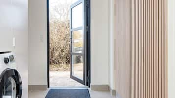 A laundry room with a washing machine, a door leading outside, and a tiled floor.