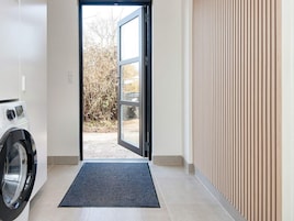 A laundry room with a washing machine, a door leading outside, and a tiled floor.