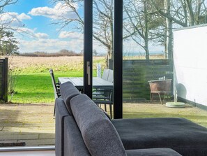 A modern outdoor seating area with a view of a grassy field and trees. - 4 Star Holiday Home in Sydals (Sydals)