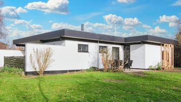 A modern single-story house with a flat roof, a small front porch, and a well-maintained lawn.