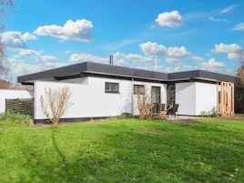 A modern single-story house with a flat roof, a small front porch, and a well-maintained lawn.