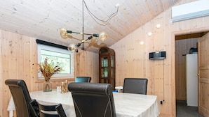 A dining area with a wooden interior, a chandelier, a table with a white tablecloth, and a vase with flowers. - 4 Person Holiday Home in Oksbol (Oksbol)