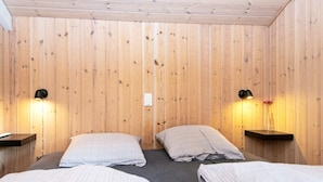 A room with two beds, wooden walls, and bedside lamps. - 4 Person Holiday Home in Oksbol (Oksbol)