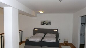 A bedroom with a bed, a small stool, a white rug, and a picture on the wall. - Kampenwand Loft Modern Retreat (Aschau im Chiemgau)