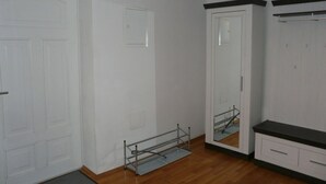 A room with a wooden floor, white walls, a large wardrobe with a mirror, and a metal rack. - Kampenwand Loft Modern Retreat (Aschau im Chiemgau)