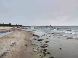 A beach with a pier extending into the water, sandy shore, and a cloudy sky. - 4 Person Holiday Home in Gilleleje (Gilleleje)