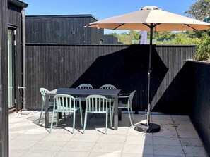 A patio with a table and chairs, a large umbrella, and a wooden fence.