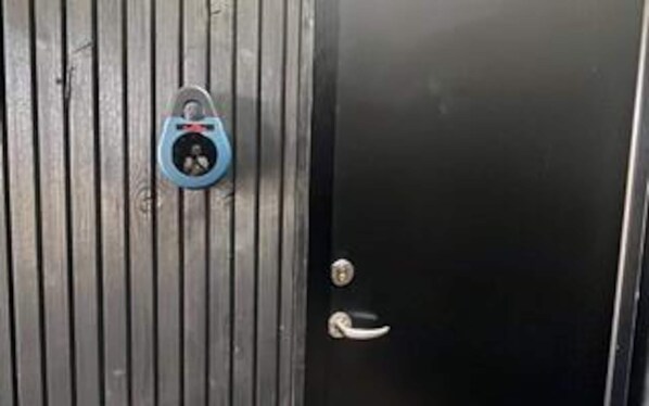 A black door with a vertical metal panel and a blue padlock.