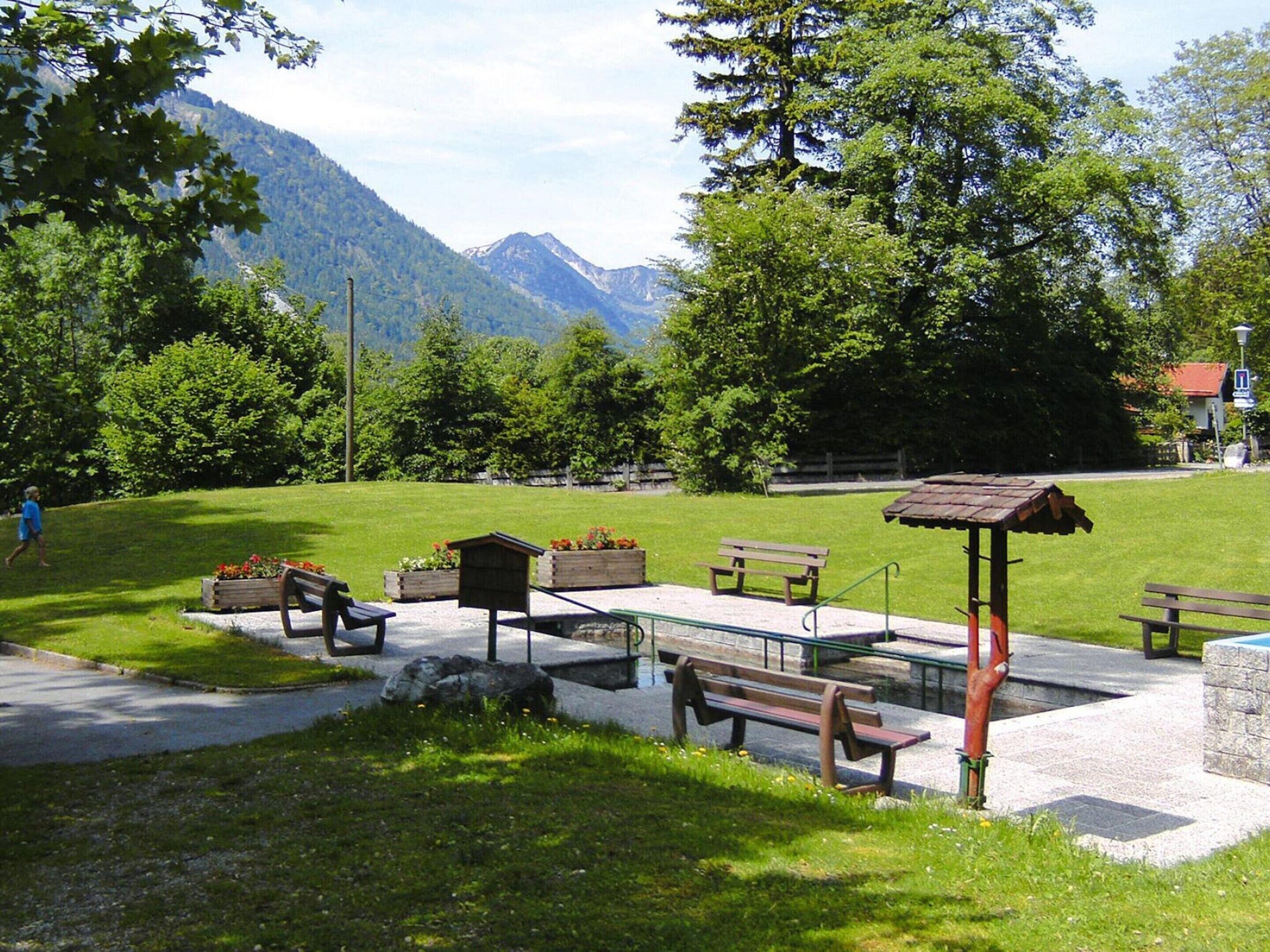A park with benches, a wooden shelter, and flower boxes.