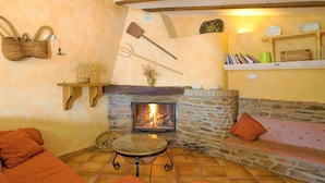 A cozy room with a stone fireplace, a wooden ceiling, a shelf with books, and a cushioned seating area. - Holiday Home in Laroya With Mountain Views (Laroya)