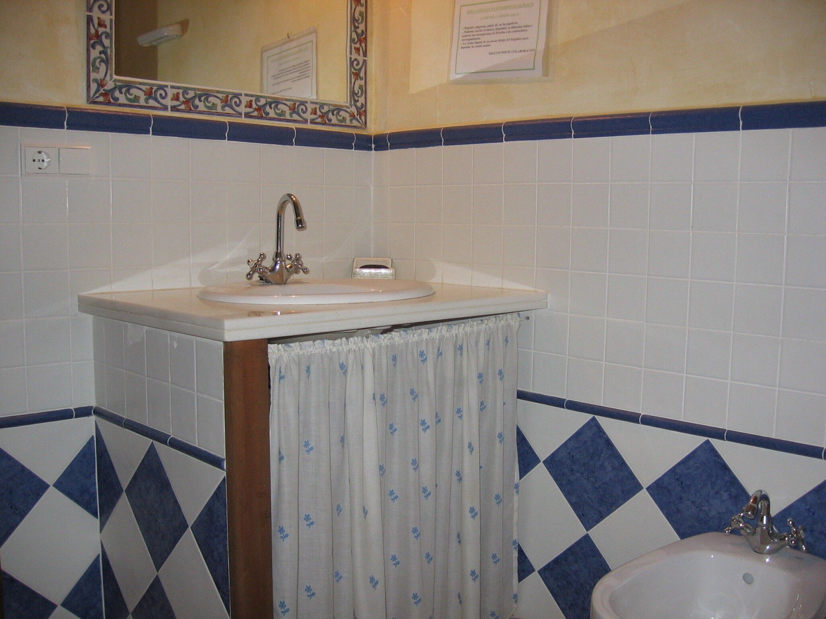 Un baño con lavamanos, espejo y azulejos estampados.