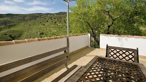 A balcony with a view of a green landscape, a table, and a bench. - Holiday Home in Laroya With Mountain Views (Laroya)