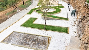 A landscaped garden with geometric pathways, a central tree, and a stone wall. - Holiday Home in Laroya With Mountain Views (Laroya)