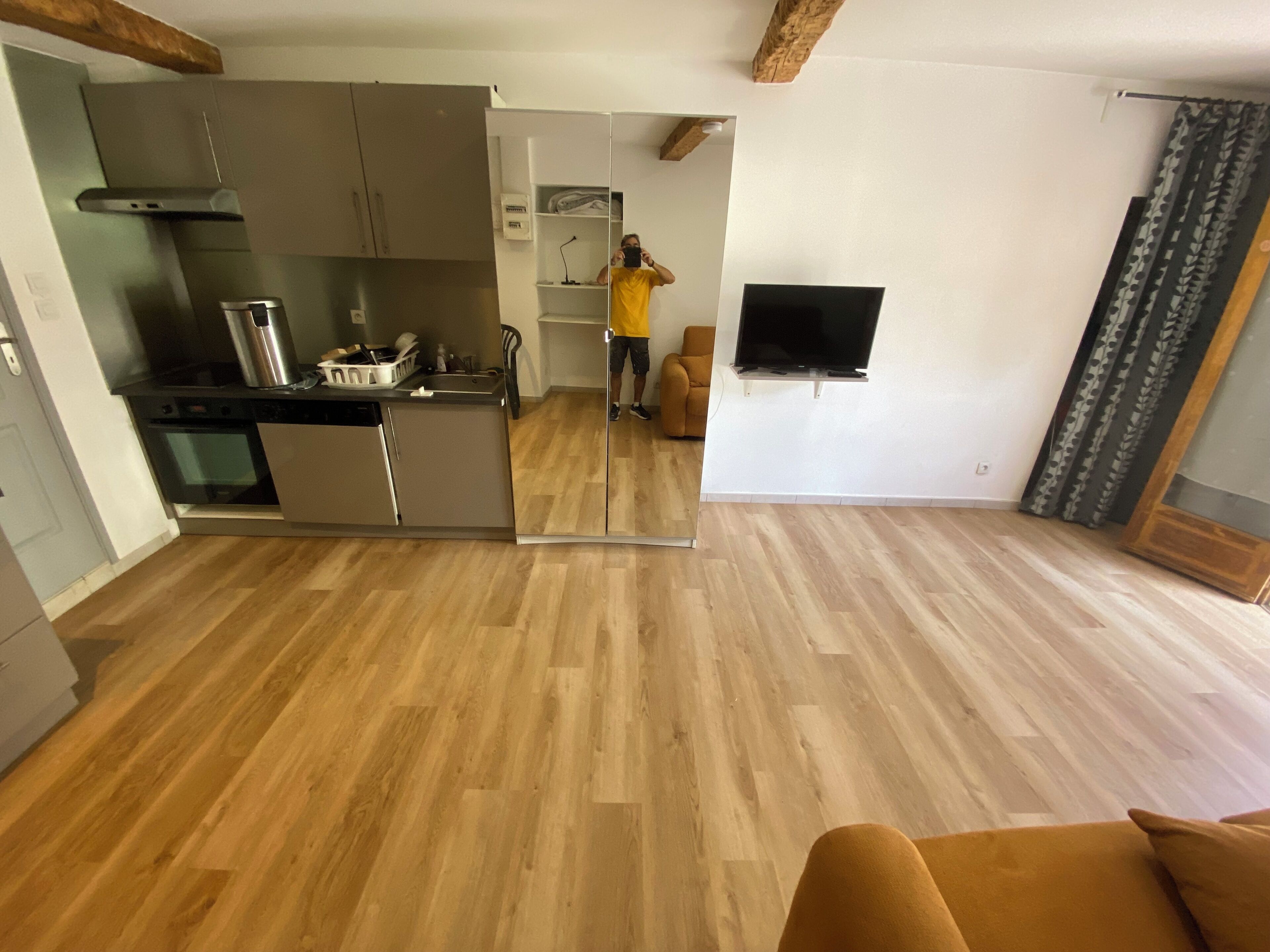 Une cuisine moderne dotée d’appareils électroménagers en acier inoxydable, d’un plancher en bois et d’un téléviseur à écran plat fixé au mur.