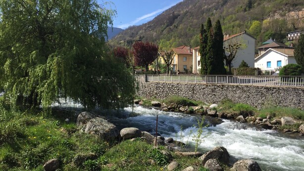 A river with a stone wall and a fence, surrounded by greenery and houses with red roofs. - Orry D'oriège, Studio de Plain-pied, Centre Ville AX, Label "Ax Qualité Confort" (Ax-les-Thermes)
