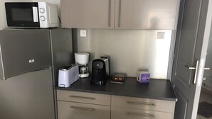 A compact kitchenette with a microwave, toaster, coffee maker, and a small box, likely containing tea or coffee pods. - Orry D'oriège, Studio de Plain-pied, Centre Ville AX, Label "Ax Qualité Confort" (Ax-les-Thermes)