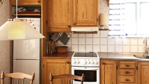 A kitchen with wooden cabinets, a stove, a refrigerator, and a window with a view.