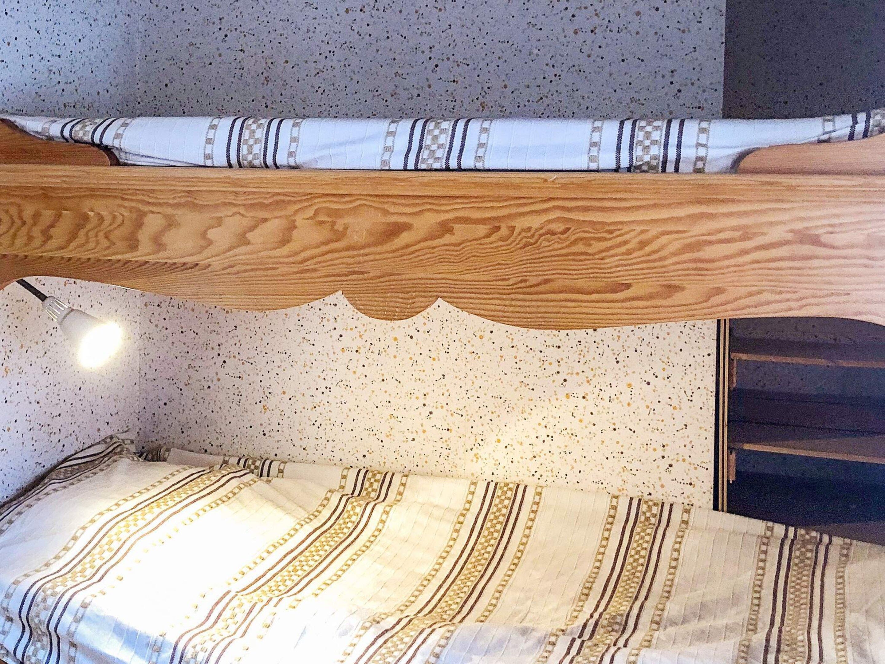 Un letto a castello con struttura in legno e copripiumino decorato.